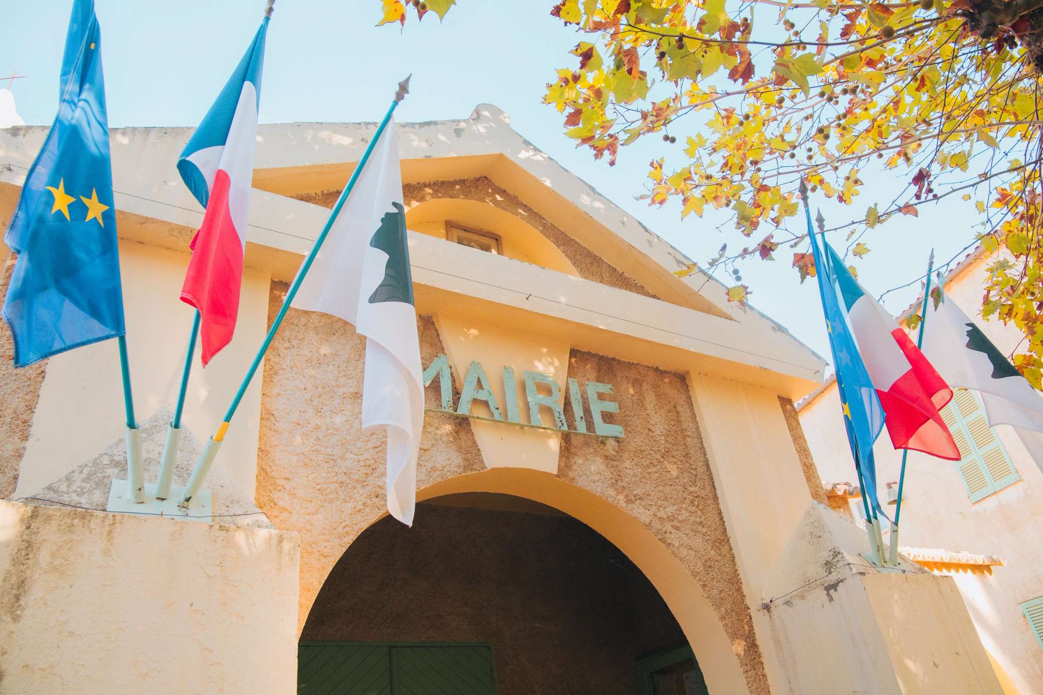 Mairie française avec drapeaux européens et tricolores sous feuillage automnal