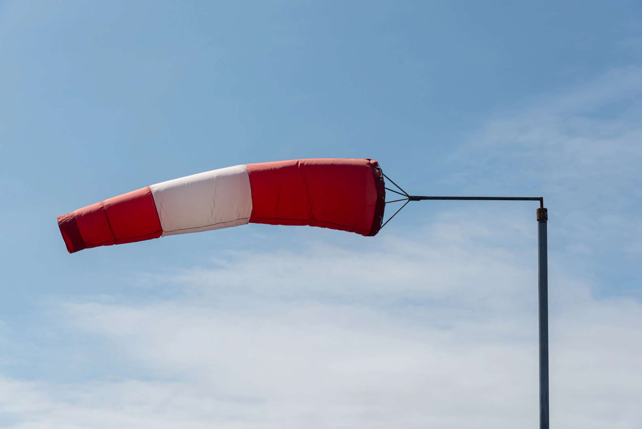 Manche à air rouge et blanc gonflée par le vent sur un ciel bleu dégagé